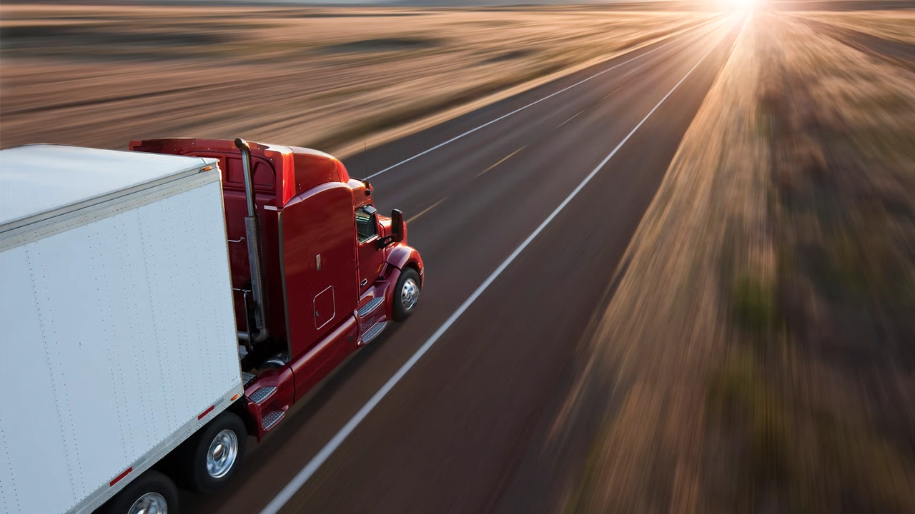 Vue de derrière et au-dessus d'un camion commercial sur la route au coucher du soleil sur une autoroute