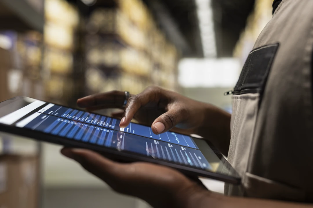 Employé d’entrepôt utilisant une tablette pour saisir des données d’expédition précises.