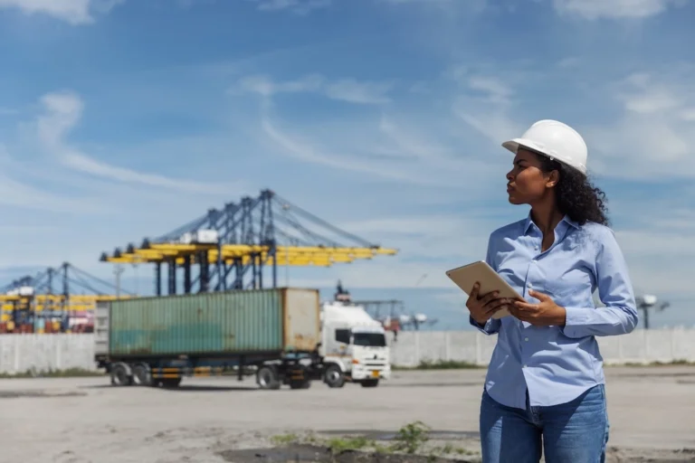 Un professionnel de la logistique utilisant une tablette près de conteneurs de fret, illustrant comment la précision des données d'expédition améliore les résultats en matière de transport de lots partiels (LTL).